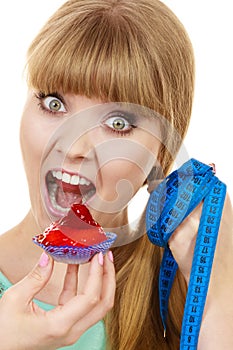 Woman holds cupcake trying to resist temptation