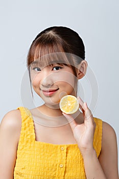 Woman holds cut juicy fruit near face skin