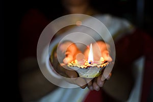 Woman holds diwali lamp on her hands