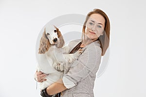 A woman holds a dog in her arms and both look into the camera. English cocker spaniel with honey gold coat.