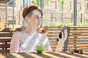 Woman holds an ebook device and a reusable coffee cup in her hands