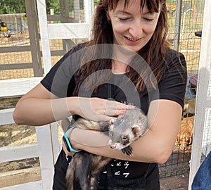 A woman holds a ferret in her arms