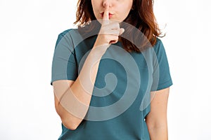 Woman holds a finger to her mouth, calling for silence. Close-up. White background. The concept of silence and secrecy