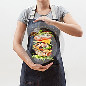 Woman holds a flying homemade burger from fresh organic ingredients on a light background.