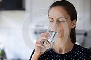 Woman holds glass drinking still water reducing thirst