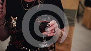 A woman holds a glass of red wine in her hand.