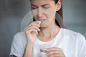 Woman holds glass of water takes painkiller for headache reducing