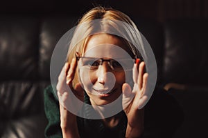 A woman holds glasses in her hands and looks at the camera. Teacher, attention, learning something concept