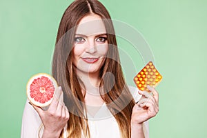 Woman holds grapefruit and pills blister pack vitamin c