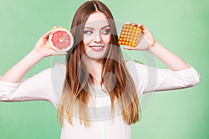 Woman holds grapefruit and pills blister pack vitamin c