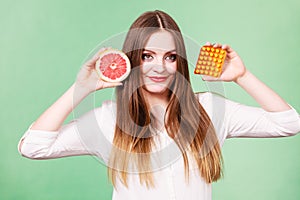 Woman holds grapefruit and pills blister pack vitamin c