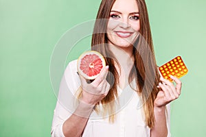 Woman holds grapefruit and pills blister pack vitamin c