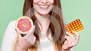 Woman holds grapefruit and pills blister pack vitamin c