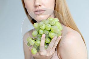 Woman holds grapes in the chest and hugs it with both hands