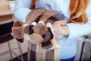 Woman holds hair extension equipment of natural hair. hair samples of different colors