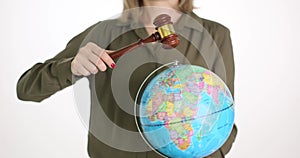 A woman holds a hammer of a judge and a globe