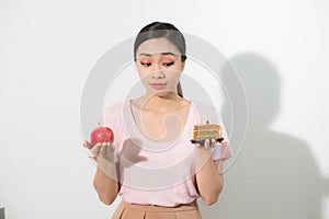 Woman holds in hand cake sweet and apple fruit choosing.