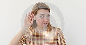 Woman holds hand near ear and listens carefully