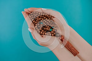 Woman holds in hand wooden mala beads strands used for keeping count during mantra meditations. Weaving and creation