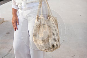 Woman holds a handmade beige knitted bag outdoors. Sustainable shopping. Wasteless lifestyle