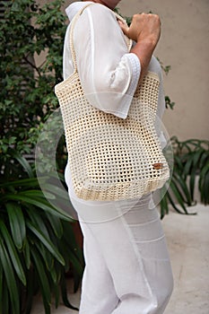 Woman holds a handmade beige knitted bag outdoors. Sustainable shopping. Wasteless lifestyle
