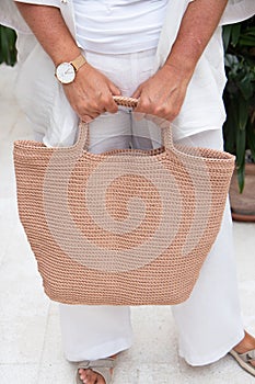 Woman holds a handmade beige knitted bag outdoors. Sustainable shopping. Wasteless lifestyle