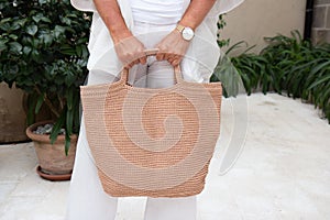 Woman holds a handmade beige knitted bag outdoors. Sustainable shopping. Wasteless lifestyle