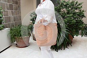 Woman holds a handmade beige knitted bag outdoors. Sustainable shopping. Wasteless lifestyle