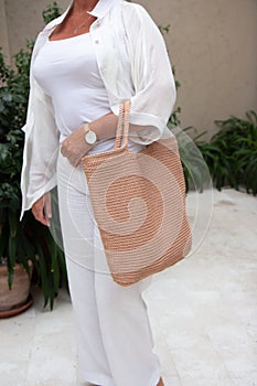 Woman holds a handmade beige knitted bag outdoors. Sustainable shopping. Wasteless lifestyle
