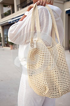 Woman holds a handmade beige knitted bag outdoors. Sustainable shopping. Wasteless lifestyle