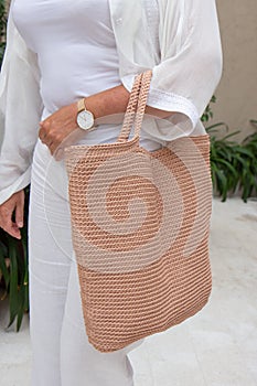 Woman holds a handmade beige knitted bag outdoors. Sustainable shopping. Wasteless lifestyle