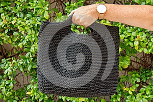 Woman holds a handmade black knitted bag in her hand near her legs outdoors. Sustainable shopping. Wasteless lifestyle