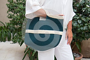 Woman holds a handmade blue knitted bag outdoors. Sustainable shopping. Wasteless lifestyle