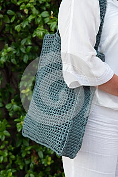 Woman holds a handmade knitted bag outdoors. Sustainable shopping. Wasteless lifestyle