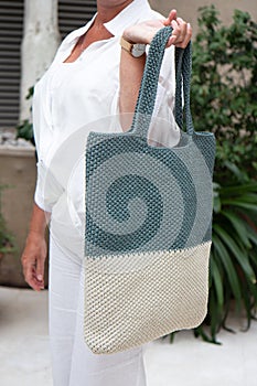 Woman holds a handmade knitted bag outdoors. Sustainable shopping. Wasteless lifestyle