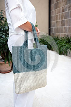Woman holds a handmade knitted bag outdoors. Sustainable shopping. Wasteless lifestyle