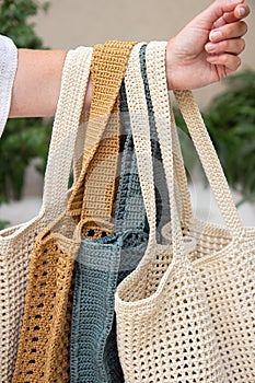 Woman holds a handmade many knitted bags outdoors. Sustainable shopping. Wasteless lifestyle