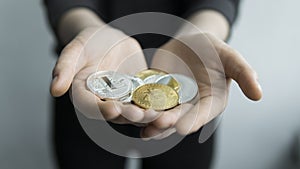 Woman holds in hands physical cryptocurrency coins - golden and silver bitcoins, ethereum and silver litecoin. Profit