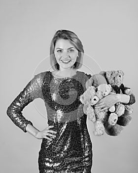 Woman holds heap of teddy bears on blue background. Lady with blond hair hugs cute toy bears.