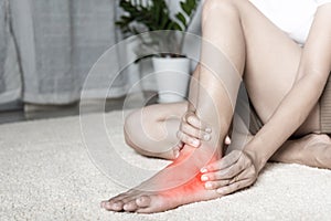 Woman holds her ankle injury feeling pain in her foot at home