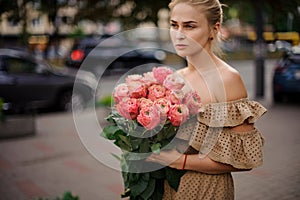 Woman holds in her hand bouquet of stylish bright peony roses