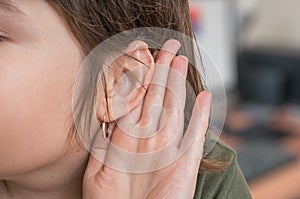 Woman holds her hand near ear and listening carefully