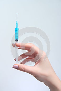 Woman holds in her hand syringe with blue solution