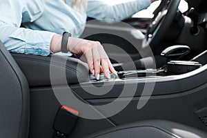 Woman holds her hand on the wheel of the car settings. Ð¬odern car features concept