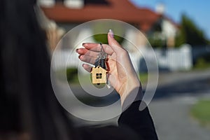 A woman holds in her hands the keys to the house against the background of residential buildings. Concept for buying and renting