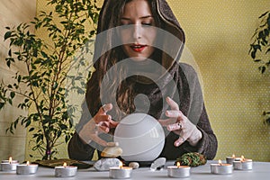 woman holds her hands over a crystal ball of predictions