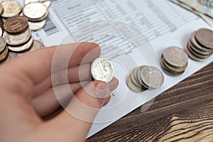 A woman holds in her hands Russian money, a piece of paper with numbers on top of a receipt for payment of utilities. Background