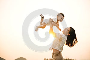 A woman holds her newborn baby up high