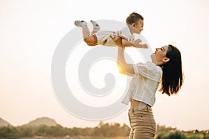A woman holds her newborn baby up high