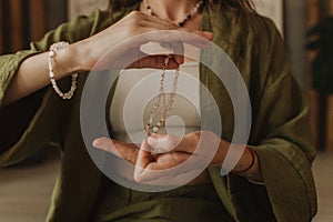 Woman holds jewelry made of natural stones in her hand, her hands are decorated with rings and bracelets. Handicrafts and